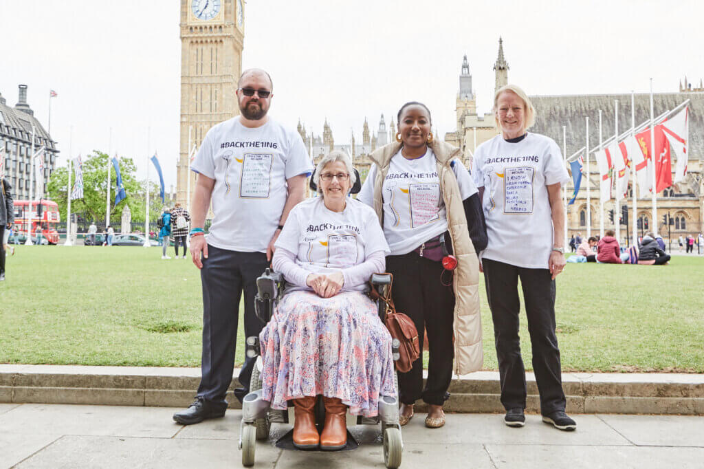 Coproduction group members posed near the seat of power – the Houses of Parliament. Flags flutter in the background.