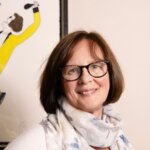 Clare: a smiling white woman with brown hair and glasses