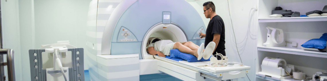 A person on an MRI scanner bed being assisted by a clinician.