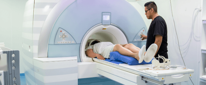 A person on an MRI scanner bed being assisted by a clinician.